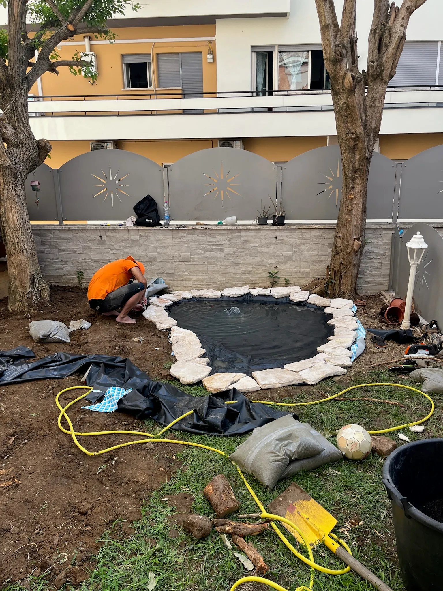 Posa del telo impermeabile e del bordo in pietra con la pompa in funzione