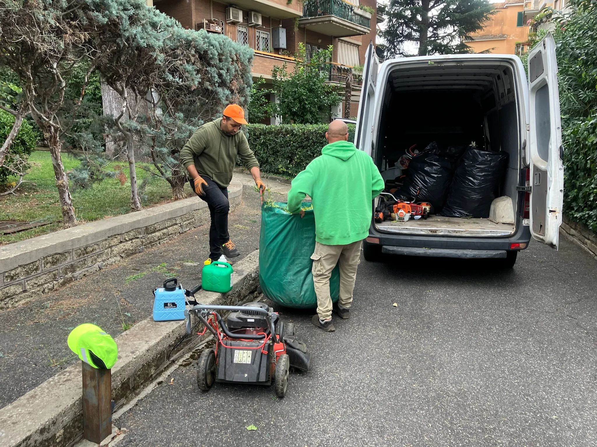Operai caricano sacchi di sfalci e potature nel furgone per lo smaltimento