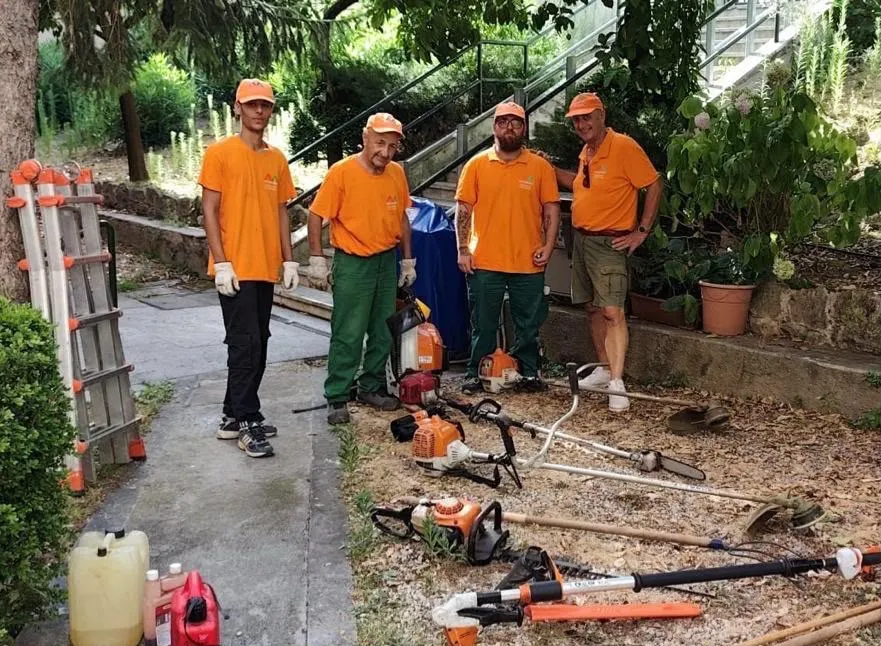 Il team Multiservizi in divisa arancione con l'attrezzatura per la manutenzione del verde